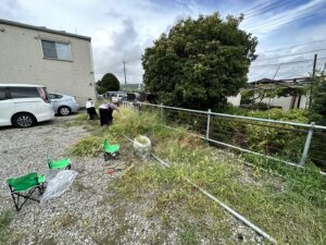 駐車場に生えている雑草を刈っているスタッフ